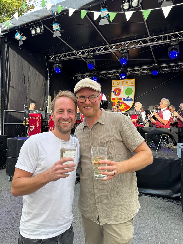 Zwei Gäste stoßen vor der Bühne mit Wein an, Lother Weinfest 2025